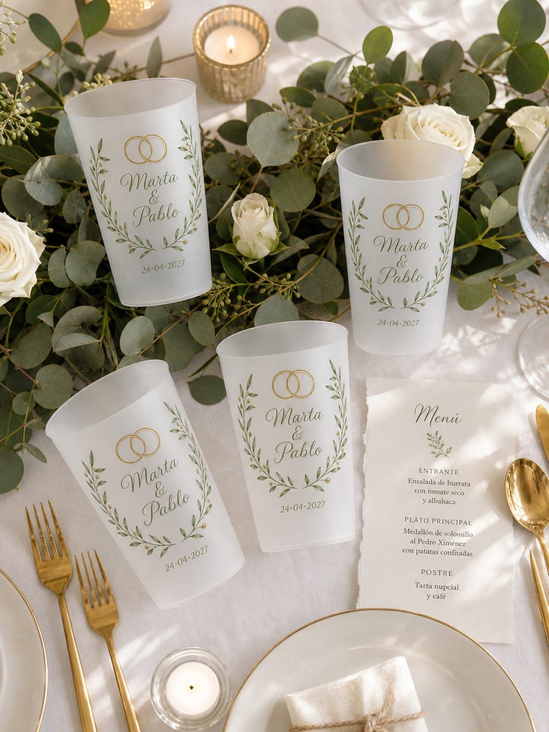 Cuatro vasos personalizados sobre la mesa del banquete, junto al menú y la vajilla
