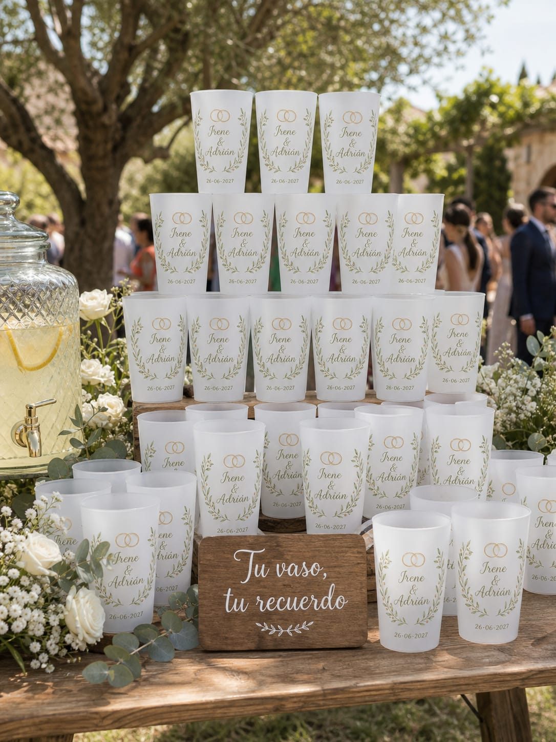 Mesa de bienvenida con vasos apilados y un cartel de madera que dice «Tu vaso, tu recuerdo»